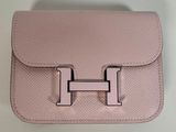 pink leather handbag with a metal handle on a white surface