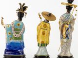 three figurines of asian women with hats and a fan