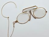une paire de lunettes et une chaîne posées sur une surface blanche