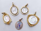 four gold and mother of pearl pendants and a mother of pearl pendant