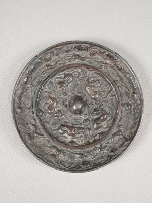 un vieux bouton en métal sur lequel est représenté un visage, posé sur une surface blanche