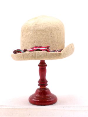 un chapeau posé sur un support, sur une table blanche