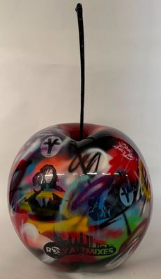 une pomme colorée, ornée de graffitis, posée sur une table