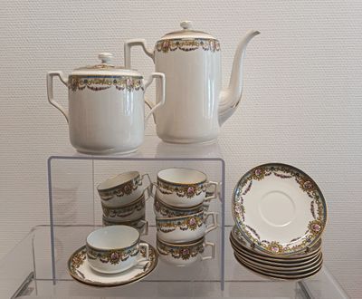 une étagère en verre sur laquelle sont posés une théière, des tasses et des soucoupes
