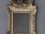 un miroir au cadre doré ouvragé accroché à un mur gris
