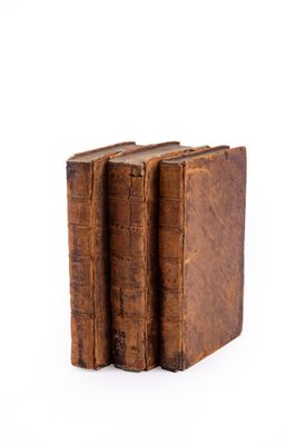 two old books sitting on top of each other on a white surface