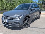une Volkswagen Tiguan grise garée sur un parking près des arbres