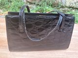 black leather handbag on a wooden table with a stone wall in the background
