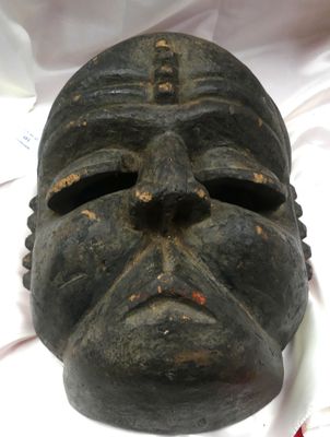 un masque noir posé sur un tissu blanc posé sur une table