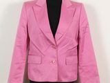 un blazer rose posé sur un mannequin contre un mur blanc