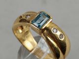 a close up of a gold ring with a blue topaz stone