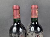 two bottles of red wine sitting next to each other on a table