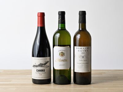 trois bouteilles de vin sont alignées sur une table en bois
