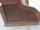 a wooden clock on a stand on the floor