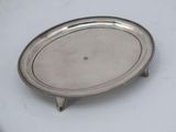 an oval silver tray with a beaded edge on a white surface