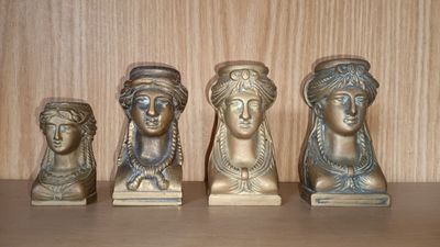 quatre petits bustes en bronze représentant des femmes, posés sur une étagère dans une pièce