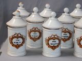 several white canisters with gold trim are lined up on a table