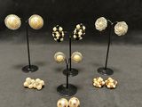 six pairs of earrings and a pair of earrings on a stand