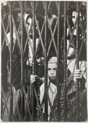 une photo en noir et blanc d'un jeune garçon derrière une clôture