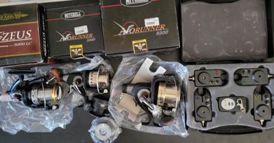 many fishing reels and other fishing equipment on the table