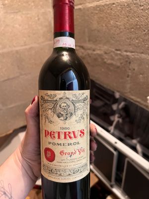 une personne tenant une bouteille de vin rouge à la main