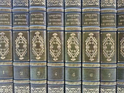 several old books are lined up on a shelf in a library