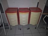 trois commodes rouges et jaunes montées sur roulettes dans une pièce