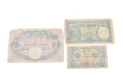 Trois anciens billets de banque français sont posés sur une surface blanche