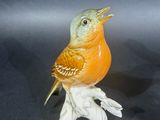 pair of ceramic birds sitting on a branch, one with its beak open