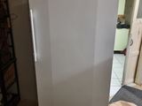 un réfrigérateur blanc posé dans une pièce où se trouve une étagère métallique