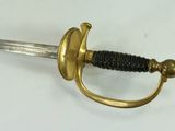 a gold colored sword with a black handle on a white surface