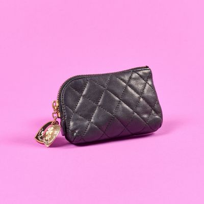 un petit sac à main noir auquel est accrochée une chaîne dorée