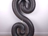une image représentant un objet noir en forme de spirale posé sur un plancher en bois