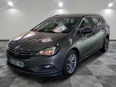 the grey car is parked on a checkered floor in a showroom