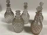 quatre bouteilles en verre ornées de nombreux petits motifs, posées sur une table