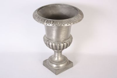 un vase en argent posé sur une surface blanche