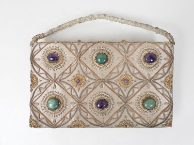 sac à main orné de perles, avec des pierres vertes et violettes sur fond blanc