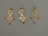 three gold pendants of different shapes and sizes on a white surface