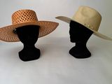 deux chapeaux posés sur une tête de mannequin, sur une surface blanche