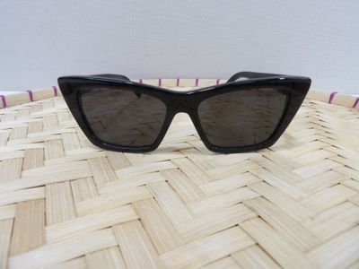 a close up of a pair of black sunglasses on a woven basket