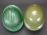 two green hard hats sitting next to each other on top of a table