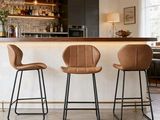 trois tabourets de bar en cuir marron sont disposés devant un bar