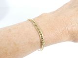 a woman ' s arm with a gold bracelet on it