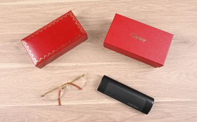une boîte rouge et une paire de lunettes posées sur un plancher en bois