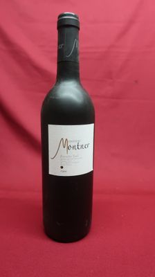 the bottle of red wine is sitting on a red cloth