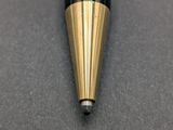 a close up of a black and gold ballpoint pen on a gray surface