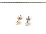 a pair of pearl earrings and a chain on a white background