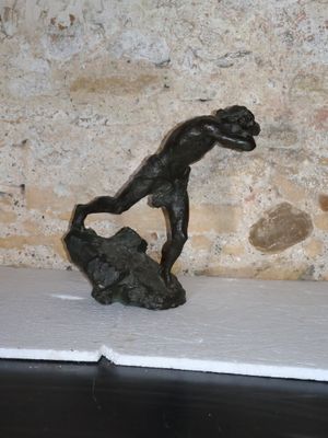 une petite statue représentant un garçon assis sur un rocher