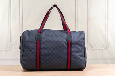 un sac de voyage bleu et rouge posé sur une table en bois