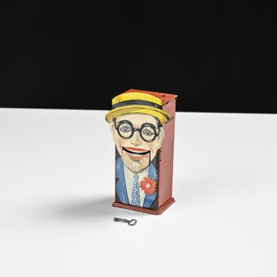 figurine de bande dessinée représentant un homme à lunettes et coiffé d'un chapeau, dans une boîte